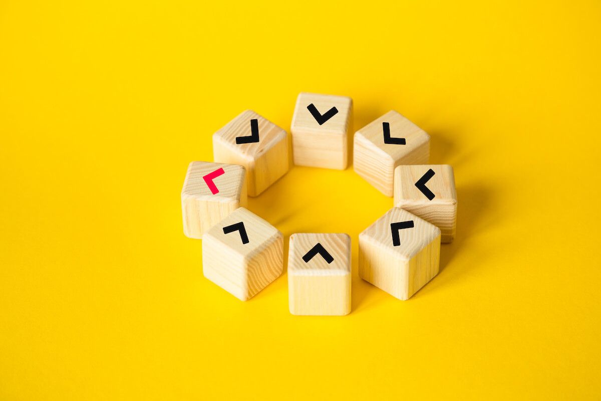 Wooden blocks with seven black arrows and one red arrow