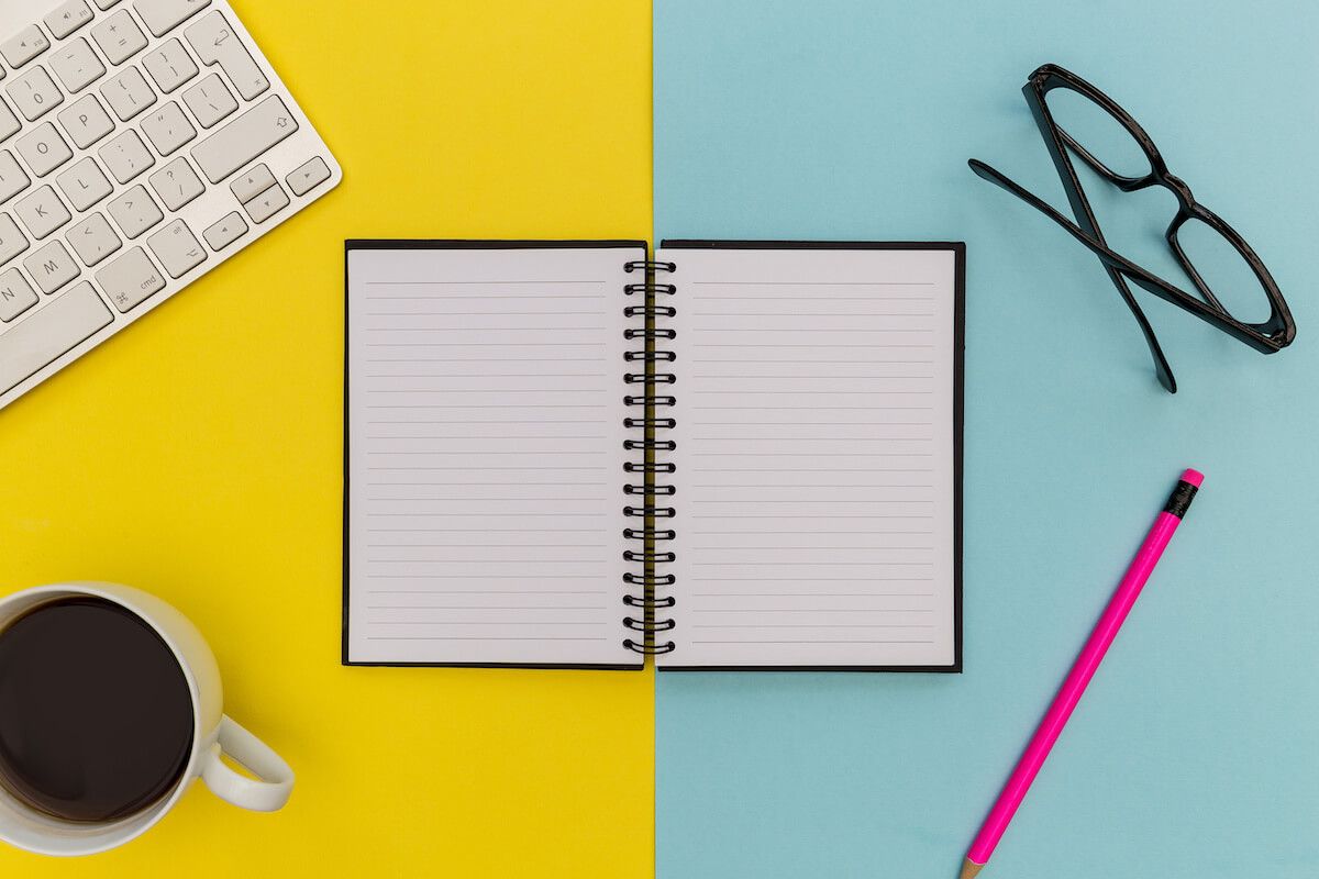 Organizing information: notebook, pencil, glasses, keyboard and a cup of coffee