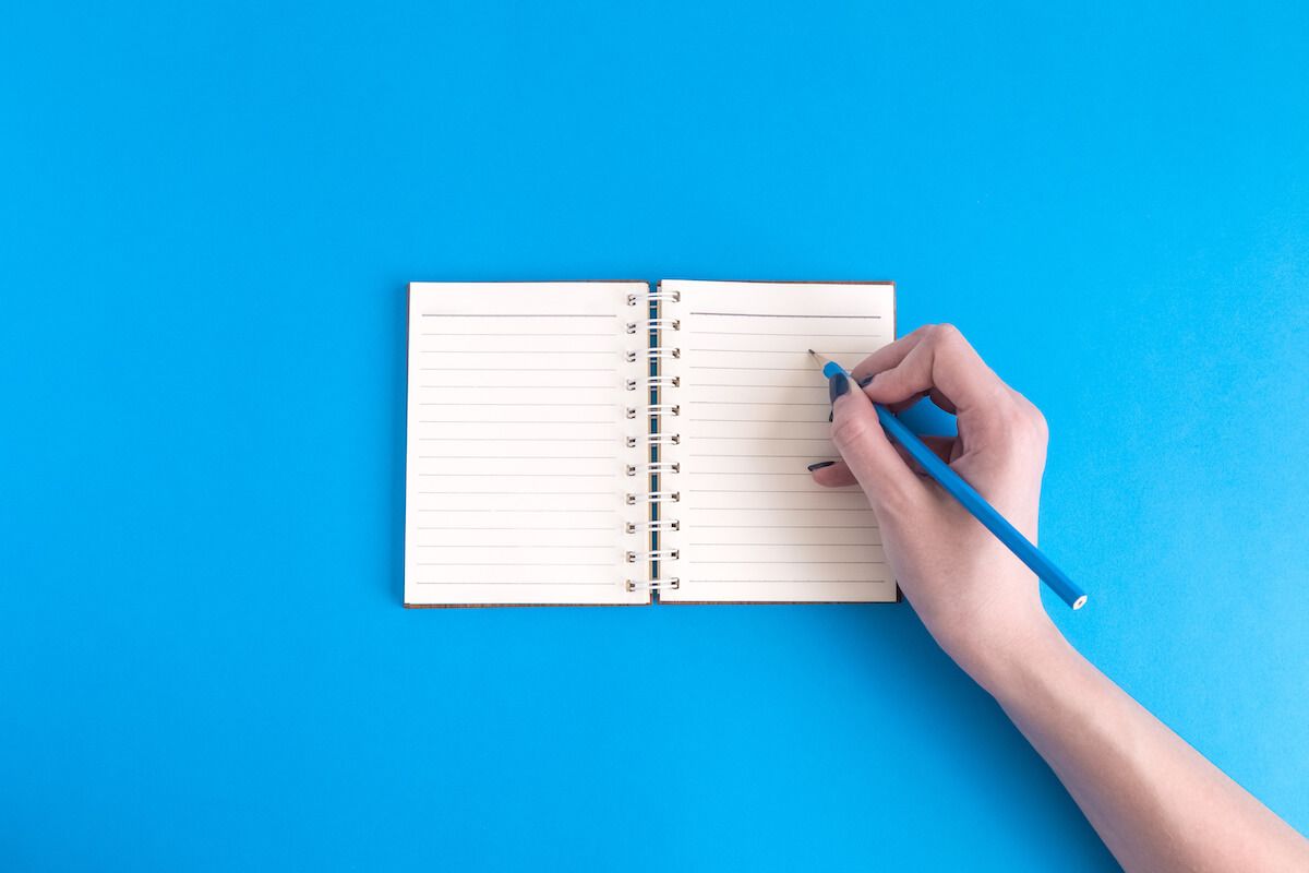 Person writing on a small notebook