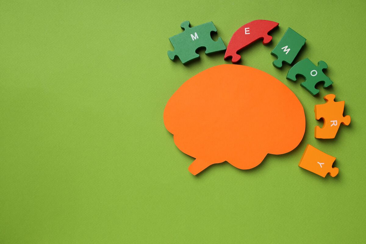 Orange brain model and puzzle pieces spelling the word MEMORY