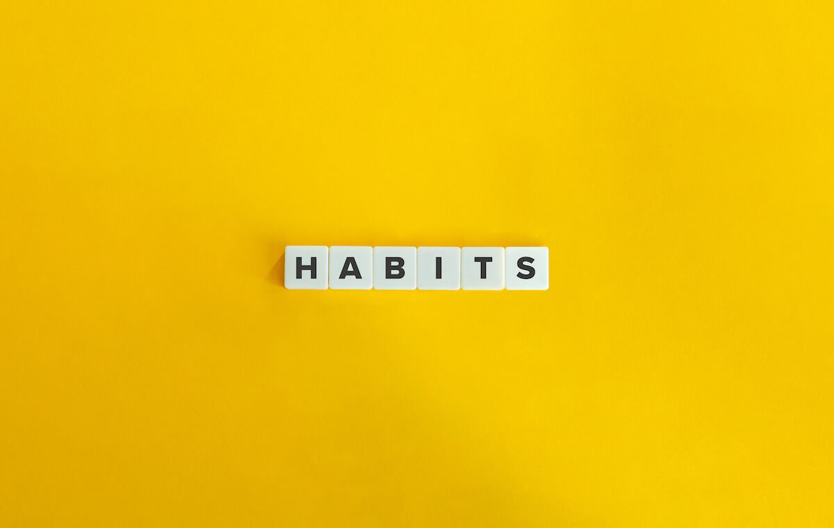 HABITS spelled using scrabble tiles on a yellow background