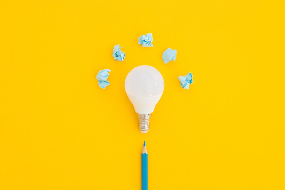 Cognitive approach: a pencil, light bulb, and 5 pieces of crumpled paper on a yellow background
