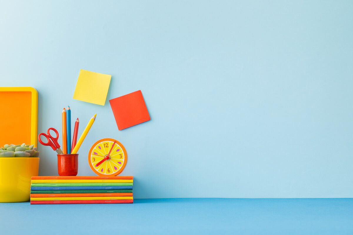 Stacked notebooks, pencils, clock, and sticky notes